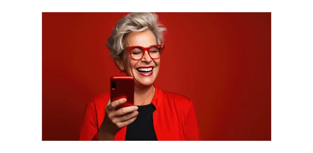 eine-altere-frau-lachelt-und-lacht-mit-ihrem-telefon-vor-einem-farbigen-hintergrund